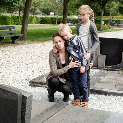 young family visiting the grave of their husband and father